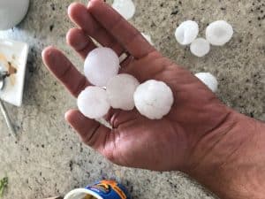Hand holding golf ball sized hail in Castle Rock.